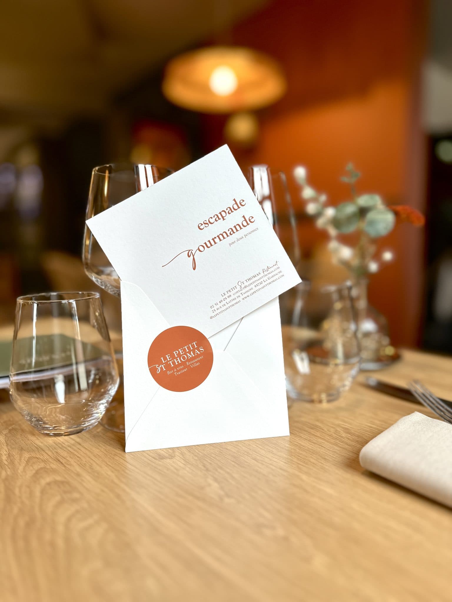 A “gourmet getaway” gift voucher from Le Petit Saint Thomas, resting on a laid table