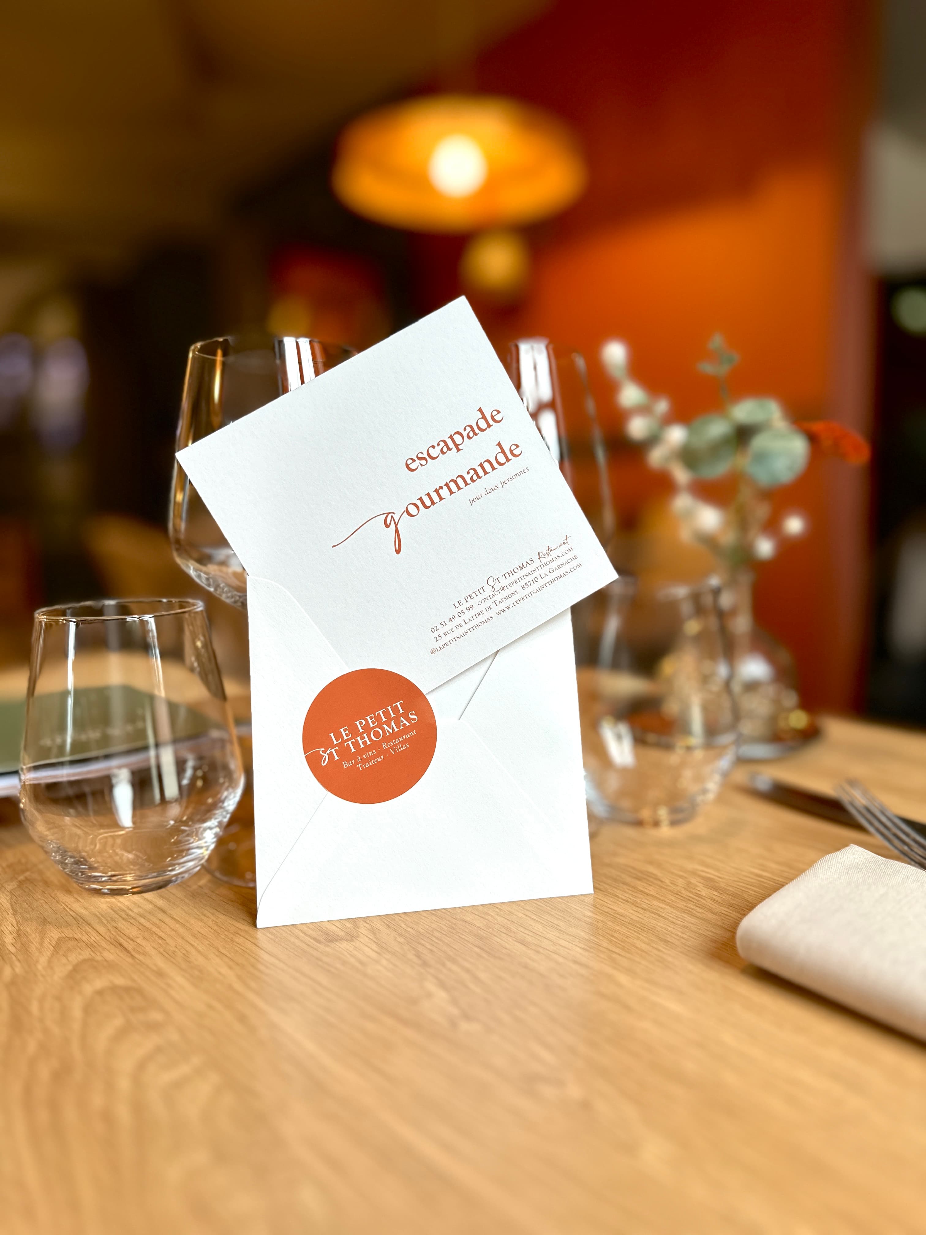 Un bon cadeau « escapade gourmande » du Petit Saint Thomas, posé sur une table dressée